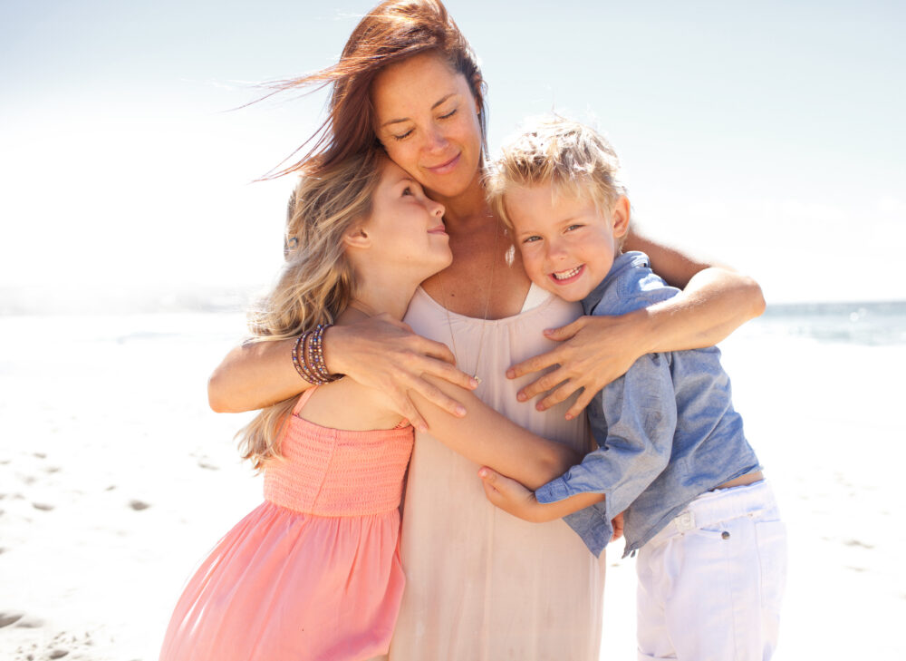 Mother holding children under arms on beach - Friesenhörn-Nordsee-Kliniken GmbH